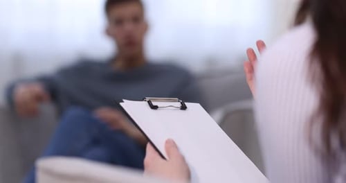 Psychologue professionnel prenant des notes sur le bloc-notes pendant une séance de thérapie avec un patient