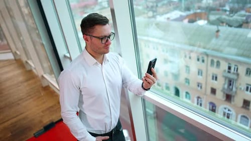 Man Using Smartphone by Office Window