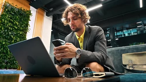 Young Adult Working on Laptop and Using Phone