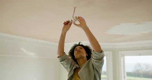Woman Repairing Electrical Fixture in Renovated Room