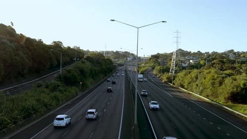 A wide handheld shot of a busy road with vehicles moving at high speed on a sunny and clear afternoo