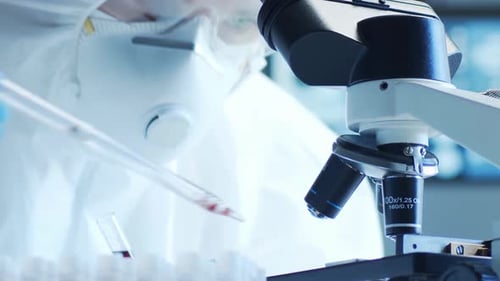Scientist Examining Blood Sample Under Microscope in Lab