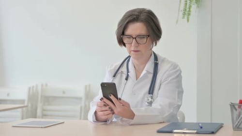 Senior Doctor Browsing Smartphone in Clinic