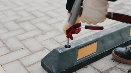 Worker Fastening Rubber Parking Wheel Stop on Tiled Pavement Close Up