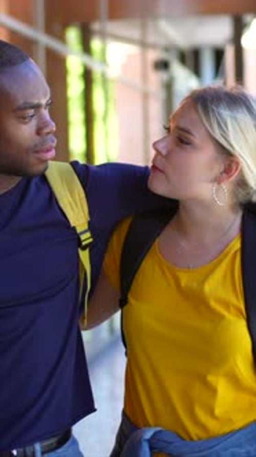 Casal multiétnico abraçando uma caminhada pela universidade