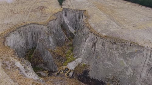 Geological Fault Splitting Farmland Near Mountain Range Exposing Stratified Ground Layers and