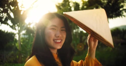 Smiling Woman Puts on Traditional Hat at Sunset