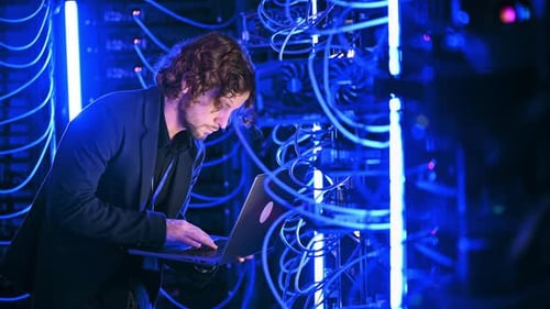 Young Adult Troubleshooting Servers with Laptop