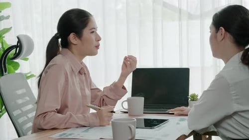 Two Young Enthusiastic Businesswoman Working Together in the Office Workspace