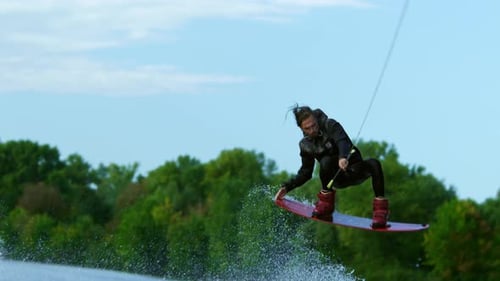 Man Wakeboarding and Jumping on a River