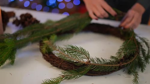 Woman Creating Christmas Wreath with Evergreen Branches