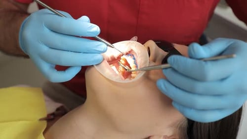 Dentist Checks Patient's Teeth with Hand Eye and Medical Equipment in Office