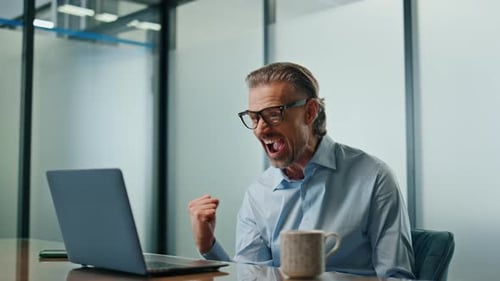 Excited man celebrates success in office workplace