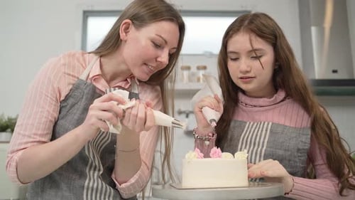Mother and daughter decorating cake together in the kitchen