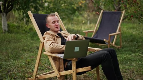 Young Adult Man Using Laptop in Lawn Chair