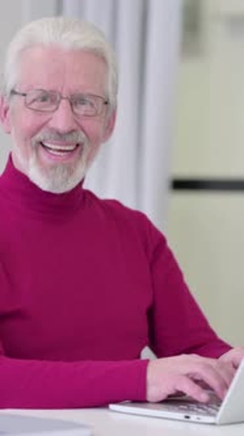 Senior Man Smiling and Typing on Laptop