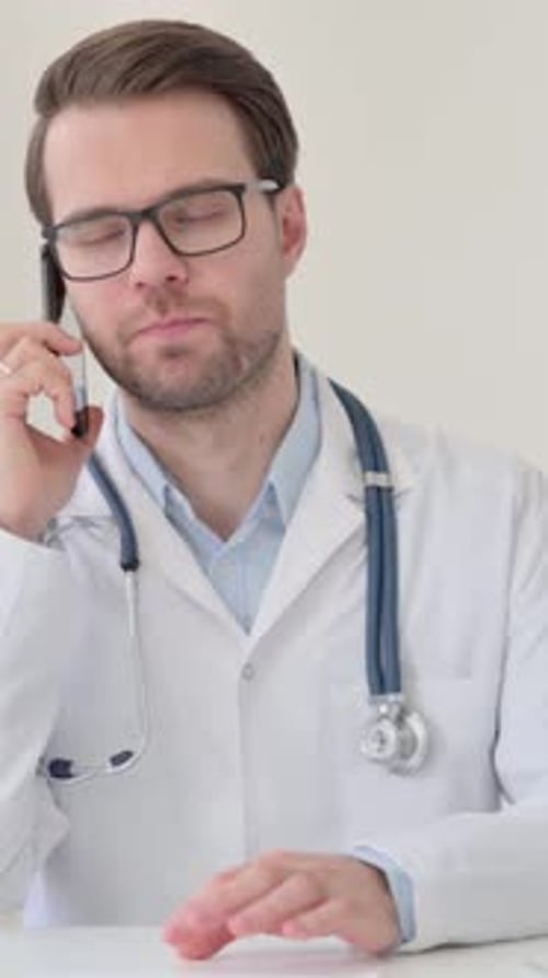 Concerned Doctor in White Coat Talking on Smartphone