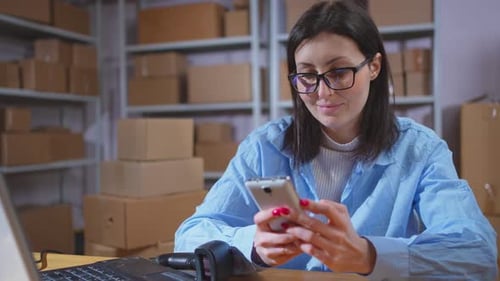 Portrait of a Positive Young Female Startup Employee with a Phone in Her Hands Smiling Close Up