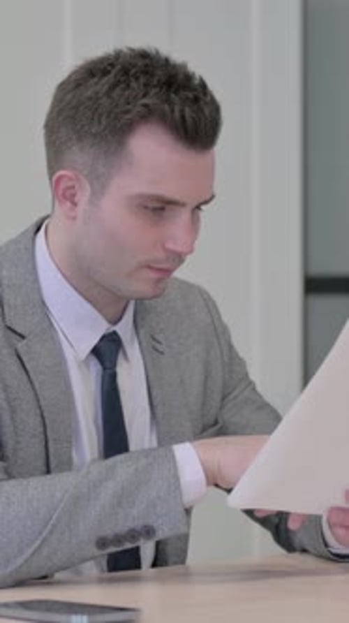 Happy Young Adult Man Reading Good News at Workplace