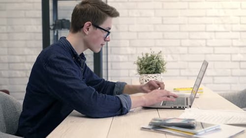 Teenager Using Laptop and Writing in Notebook