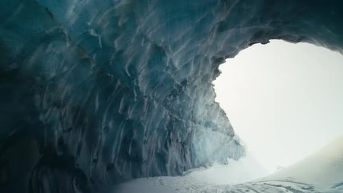 View through giant blue ice cave and abstract icy formations slow pan
