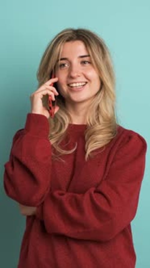 Happy Woman Talking on Mobile Phone in Blue Studio