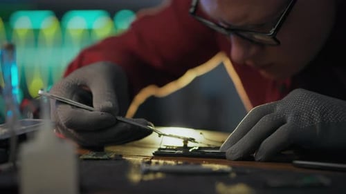 Repair. A workshop worker uses professional skills carefully using tweezers in electrical assembly