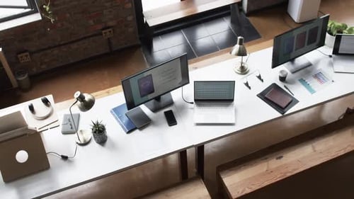 Mehrere Workstations mit Computern, auf denen App-Design und Channel-Marketing angezeigt werden