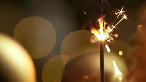 Sparkler Burning Brightly with Golden Bokeh Background