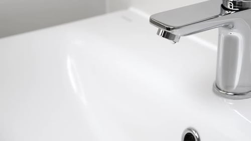 Shiny chrome faucet over white porcelain bathroom sink