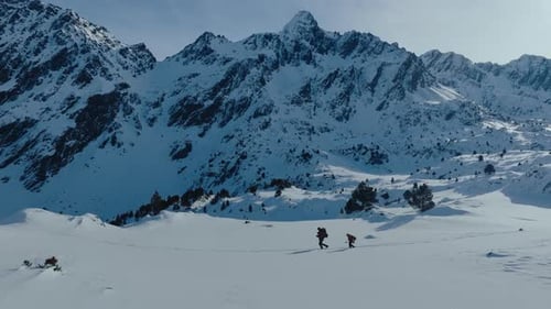 Epic Aerial View of Two Backpacker Tourist Hike Throug Snowy Mountain Landscape