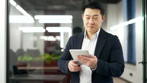 Smiling Man Holding Tablet in Modern Office