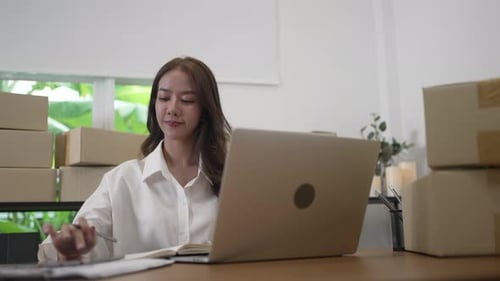 Young female entrepreneur is packing merchandise at home.