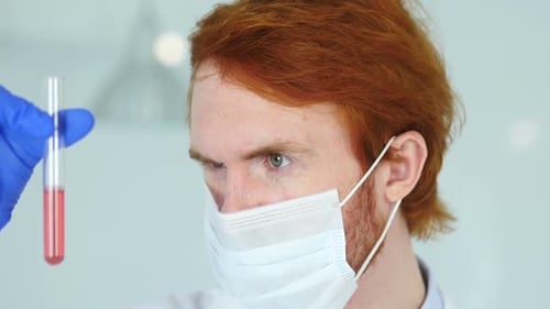 Scientist Studying Red Solution in Test Tube in Laboratory