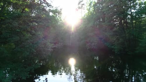 Fly slow towards sunset over dark river in Sweden