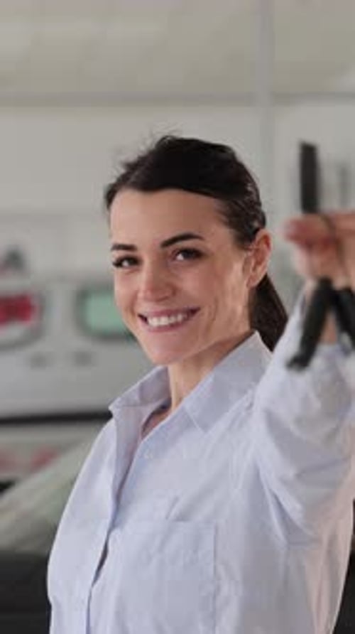 Smiling Woman Holding Keys in Automobile Showroom