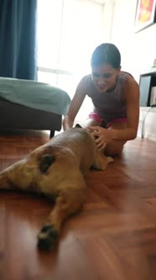 Teen Girl Massages Dog on Living Room Floor