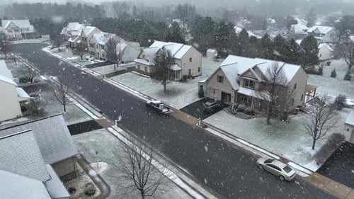 American neighborhood during winter snow storm. Snow flurries over a suburban street with detached h