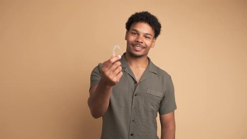Happy Young Man Showing Invisible Braces in Beige Studio