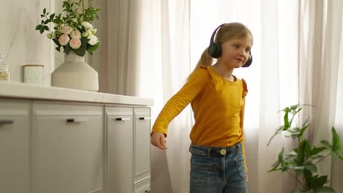 Little Caucasian Kid Child Daughter Girl in Earphones Headphones Dancing Listening Music at Home