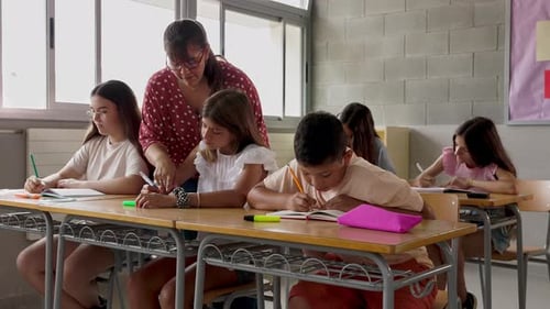 Female Teacher Assisting Elementary Student During Lesson at School