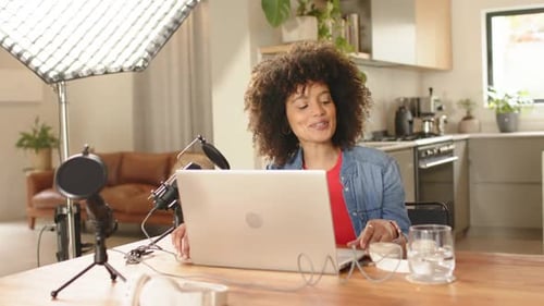 Début de la diffusion en direct, femme ajustant le micro à la lumière de la boîte à lumière à la maison, sirotant de l'eau avant de parler