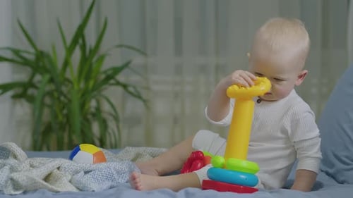 Infant Playing With Stacking Toy On Blue Bed
