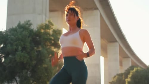Sporty Woman Spot Jogging Under Bridge at Sunrise