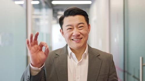 Professional Male Business Owner Showing Okay Hand Sign in Wellorganized Office