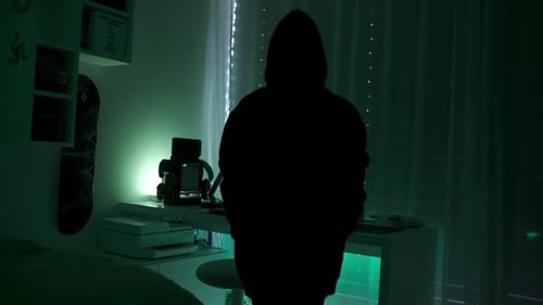 una chica hacker criminal con capucha negra que usa una computadora portátil y grandes computadoras para hackear su sistema de red