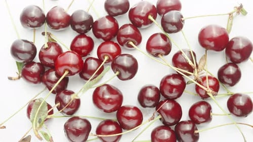 Cherry berries on a white background, One rotates in the middle.