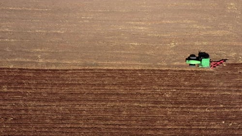 Aerial shot of a Plow processing a dry Soil field.