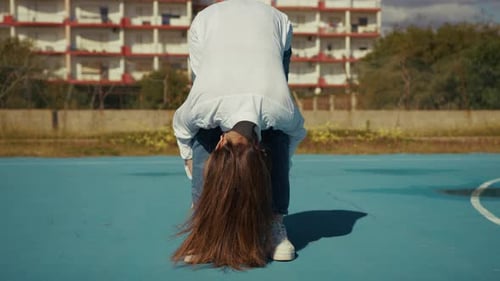 Woman Stretching On Blue Court on a Sunny Day
