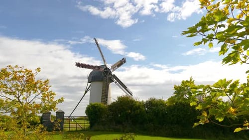 A Serene Traditional Windmill Standing Tall Against a Cloudy Blue Sky